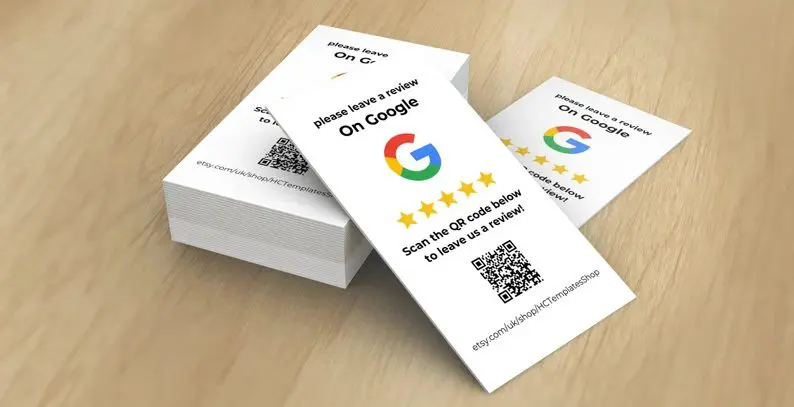 A stack of cards with the Google logo encourages you to get Google reviews for local SEO. Each card reads "Please leave a review on Google" with a five-star graphic. A QR code at the bottom links to the review page, beautifully arranged on a wooden surface.